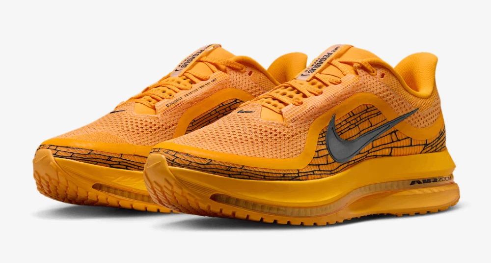 Un paio di scarpe da ginnastica Nike Air Zoom arancioni con tomaia in mesh, dettagli neri a forma di mattone e logo Swoosh grigio ai lati.